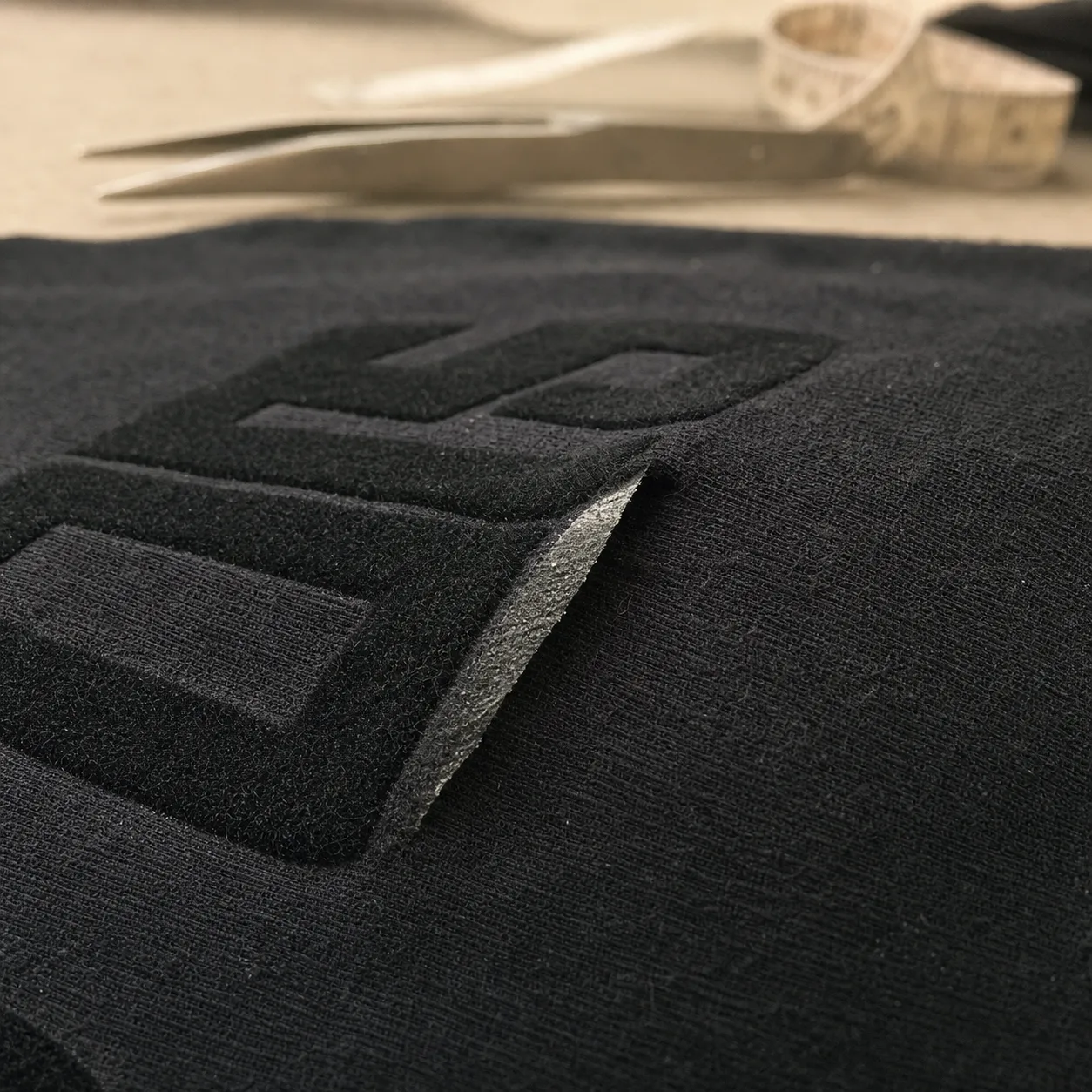Flock adhesive layer lifting away from the garment fabric