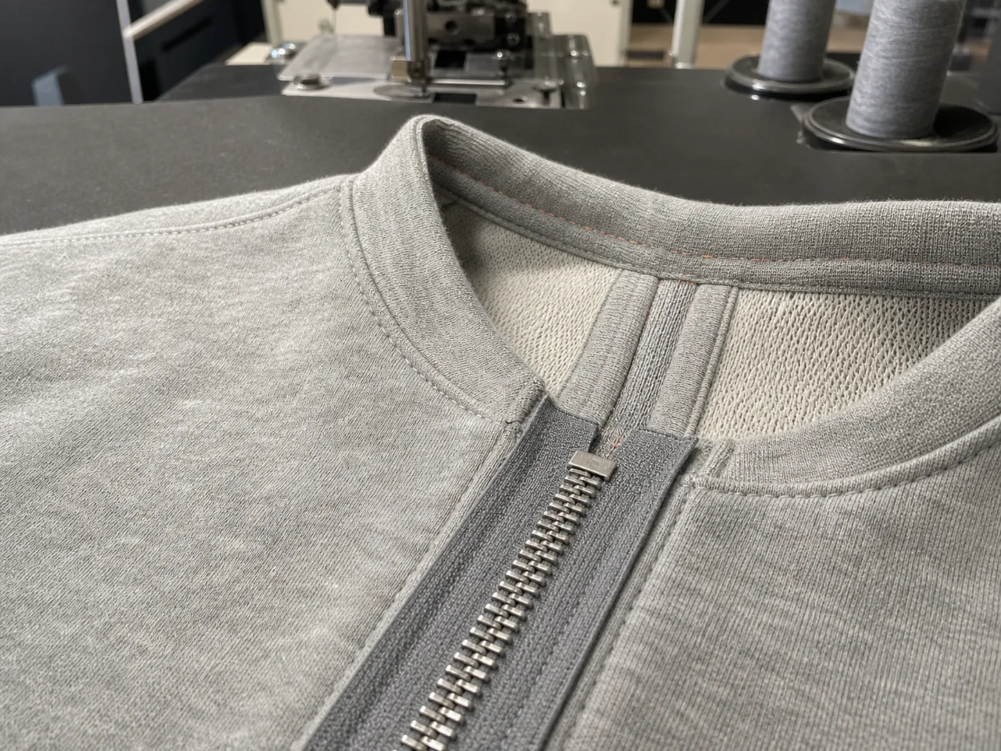 Hoodie zipper tape, top stop and neckline alignment shown at a sewing station.