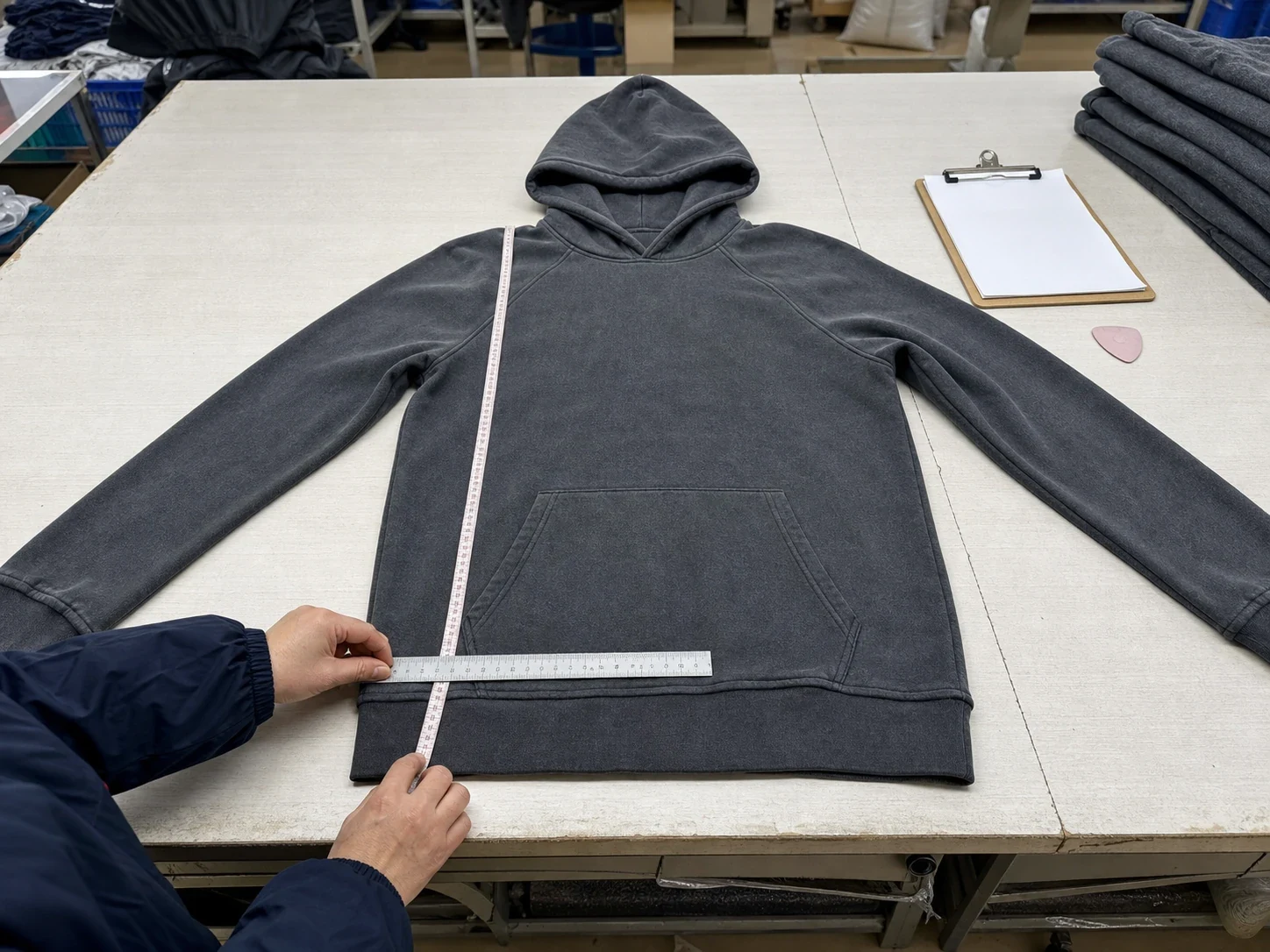 Complete charcoal hoodie with both sleeves extended for a measurement check.