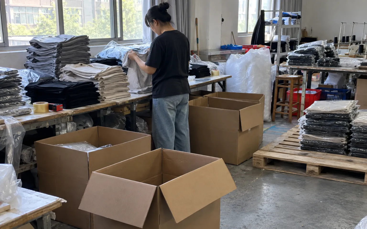 Prendas dobladas y cajas abiertas durante la preparación de un envío.