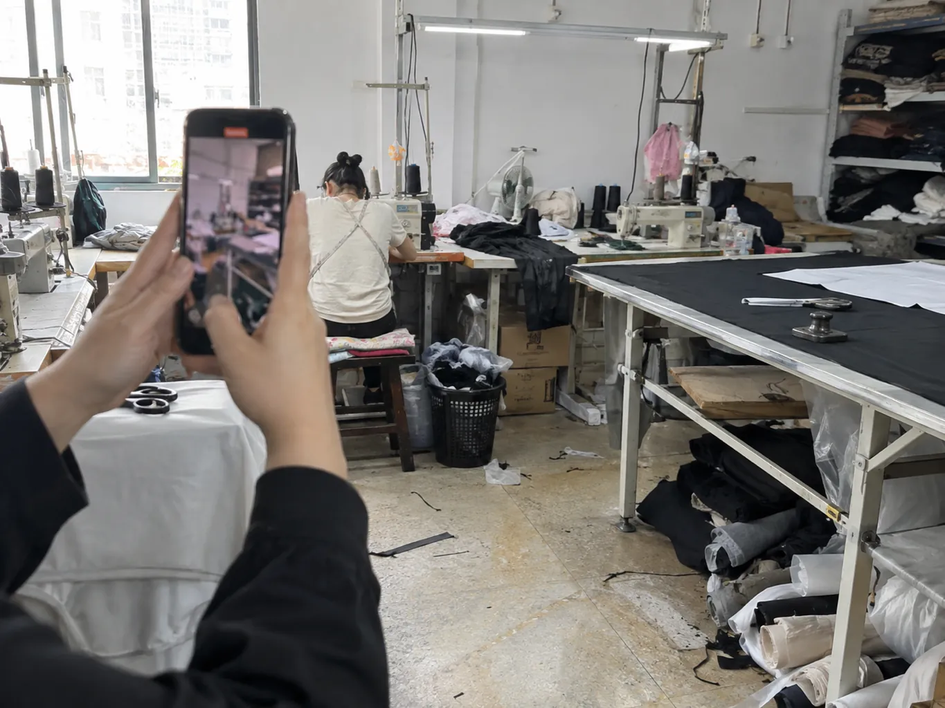 Hands hold a phone for a live tour of sewing stations.